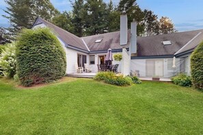 A house with a covered patio, a chimney, and a well-maintained lawn. - Charming condo in a resort community with pool access, tennis, a sauna & golf (Hartford)