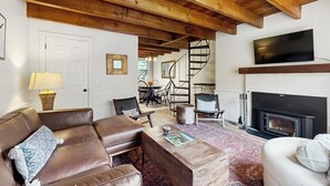A living room with a fireplace, leather sofas, a coffee table, and a TV mounted on the wall. - Quechee condo, outdoor activities nearby, kitchen, TV, wifi (Quechee)