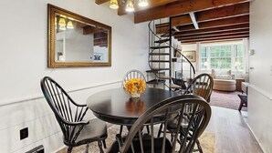 A dining area with a round table, black chairs, a mirror, and a staircase leading to another level. - Quechee condo, outdoor activities nearby, kitchen, TV, wifi (Quechee)