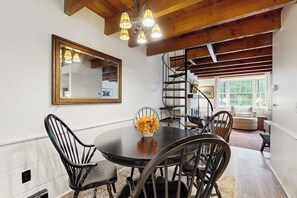 A dining area with a round table, black chairs, a mirror, and a staircase leading to another level. - Quechee condo, outdoor activities nearby, kitchen, TV, wifi (Quechee)