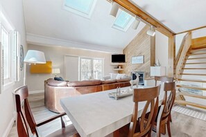 A modern interior with a dining area, a sofa, and a staircase.