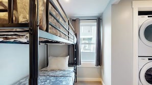 A compact room with bunk beds, a washing machine, and a window with curtains. - Centrally located apartment for the skier & outdoor enthusiast (Rutland)