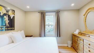 A bedroom with a bed, a dresser, a mirror, and a window with curtains.