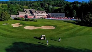 Un campo de golf con búnkeres, una casa club y un edificio con tejado rojo.