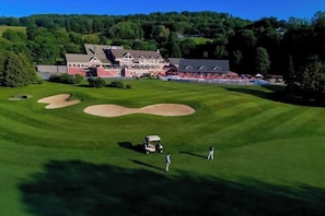 Ein Golfplatz mit Bunkern, einem Clubhaus und einem Gebäude mit rotem Dach.