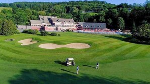 Un parcours de golf doté d’un club-house, de bunkers de sable et offrant une vue sur un ciel dégagé.