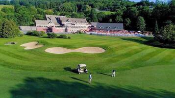 A golf course with a clubhouse, sand bunkers, and a clear sky.