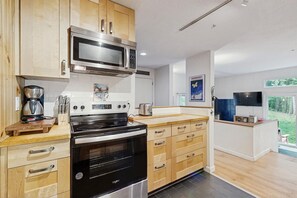 A modern kitchen with wooden cabinets, a Bosch microwave, a Whizball oven, and a toaster. - End-unit condo w/ fireplace, pool, sauna, tennis, deck, ski locker, w/d (Waitsfield)