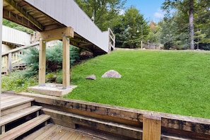 A wooden deck with a stone pathway leading to a grassy area with two large rocks. - End-unit condo w/ fireplace, pool, sauna, tennis, deck, ski locker, w/d (Waitsfield)