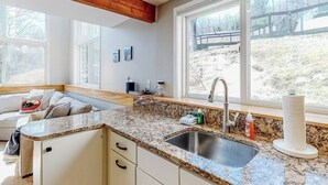 A kitchen with a granite countertop, stainless steel sink, and a window with a view of a wooden deck. - Mountain-view home with new deck, fireplace, & shared pool - walk to lifts (Warren)