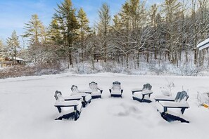 A snow-covered outdoor seating area with Adirondack chairs arranged in a semi-circle. - Comfortable condo w/ mountain & ski views, central a/c, shared patio & BBQ (Waitsfield)