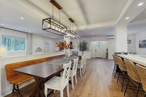 A modern kitchen with a wooden dining table, white chairs, and pendant lighting. - Comfortable condo w/ mountain & ski views, central a/c, patio & BBQ, w/d, wifi (Waitsfield)