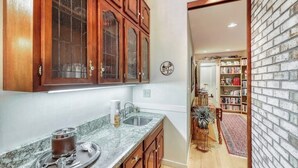 Una cocina con armarios de madera, encimera de mármol y un pequeño comedor con mesa y sillas.