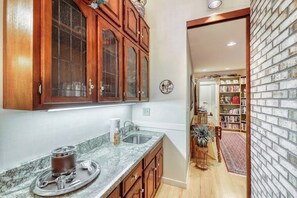 Una cocina con armarios de madera, encimera de mármol y un pequeño comedor con mesa y sillas.