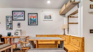 Ein gemütliches Zimmer mit einer Holzbänkl, einem Tisch und gerahmten Bildern an der Wand.