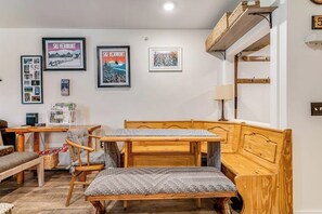 Ein gemütliches Zimmer mit einer Holzbänkl, einem Tisch und gerahmten Bildern an der Wand.