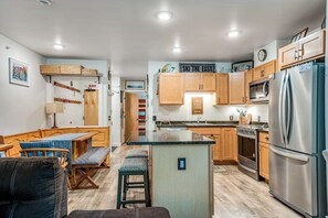 Eine kleine Küche mit Holzausstattung, einer zentralen Kochinsel, einem Kühlschrank und einer Mikrowelle.