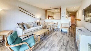 Un salon moderne avec un canapé, des fauteuils, une table à manger et des paires de skis accrochées au mur.