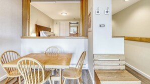 Un coin repas avec une table et des chaises en bois, un miroir au-dessus de la table et un escalier menant à une autre pièce.
