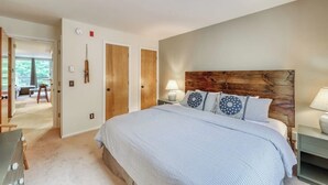 A bedroom with a large bed, a wooden headboard, a nightstand, and a lamp. - Ski-In/Ski-Out Second-Floor Condo w/ Free WiFi, Mountain Views, & a Shared Pool (Warren)
