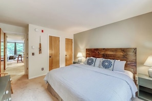 A bedroom with a large bed, a wooden headboard, a nightstand, and a lamp. - Ski-In/Ski-Out Second-Floor Condo w/ Free WiFi, Mountain Views, & a Shared Pool (Warren)