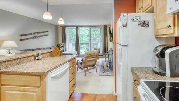 A kitchen with a built-in dishwasher, a refrigerator with a picture on it, and a coffee maker. - Ski-In/Ski-Out Second-Floor Condo w/ Free WiFi, Mountain Views, & a Shared Pool (Warren)