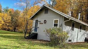 Ett envåningshus med en veranda framför, en skorsten och en liten trädgård framför huset.