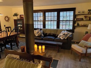 Ein gemütliches Wohnzimmer mit Kamin, einer Couch, einem Esstisch und Stühlen.