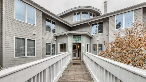 A building with a wooden deck leading to a door marked 'Paradise.' - Ski condo with locker, shuttle, fast WiFi, fireplace, washer/dryer & AC (Warren)