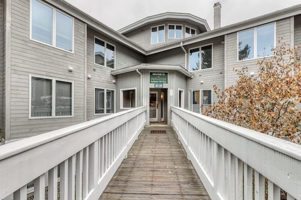 A building with a wooden deck leading to a door marked 'Paradise.' - Ski condo with locker, shuttle, fast WiFi, fireplace, washer/dryer & AC (Warren)