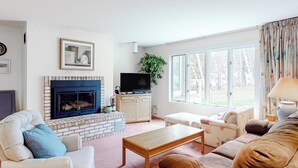 A living room with a fireplace, television, and comfortable seating. - Ski condo with locker, shuttle, fast WiFi, fireplace, washer/dryer & AC (Warren)