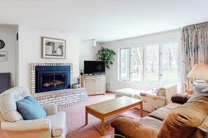 A living room with a fireplace, television, and comfortable seating. - Ski condo with locker, shuttle, fast WiFi, fireplace, washer/dryer & AC (Warren)