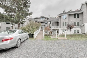 A multi-story residential building with a driveway, a car parked on the left, and a staircase leading to the entrance. - Ski condo with locker, shuttle, fast WiFi, fireplace, washer/dryer & AC (Warren)