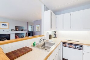 Eine moderne Küche mit weißen Schränken, einer Edelstahlspüle, einem Geschirrspüler und einer Holz Arbeitsplatte.