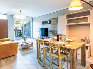 Ein modernes Wohnzimmer mit Essbereich, Fernseher und Küche.