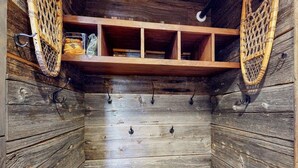 Un intérieur en bois avec une étagère, des crochets et un panier.