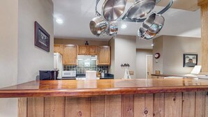 A kitchen with wooden cabinets, a microwave, and a stainless steel pot rack.