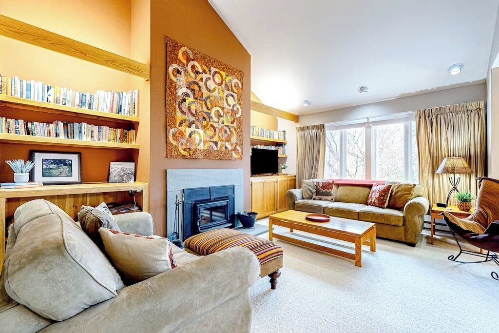 A living room with a fireplace, bookshelves, a sofa, and a coffee table.