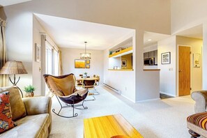 Ein modernes Wohnzimmer mit einer Couch, einem Sessel, einem Couchtisch und einer Essecke mit Tisch und Stühlen.