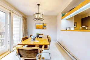 Ein Essbereich mit Holztisch und Stühlen, einer Kristallleuchtre und Kunstwerken an der Wand.