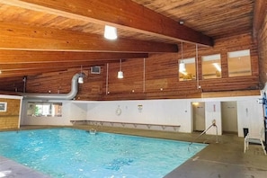 Ein Hallenbad mit Holzwänden und -decke, einem sichtbaren Fenster und einer Poolleiter.