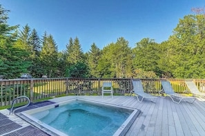Ein Schwimmbecken mit Holzterrasse, Liegestühlen und einem Holzzaun.