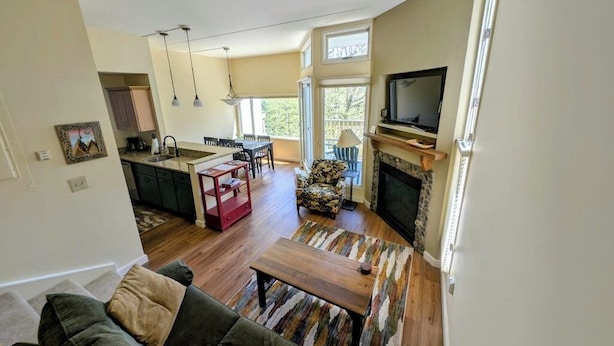 A living room with a sofa, a coffee table, a fireplace, and a television. - Convenient Skier-friendly 1BR condo, pool, gym, tennis, fireplace, wifi (Warren)