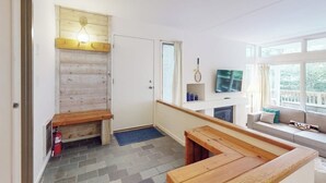 Una sala de estar acogedora con chimenea, un banco de madera, un sofá y una televisión.