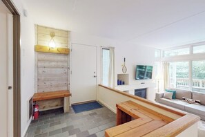 Tunnelmallinen olohuone, jossa on takka, puinen penkki, sohva ja televisio.