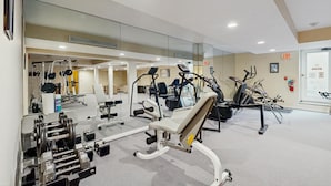 Ein Fitnessstudio mit Trainingsgeräten, Spiegeln und einer Tür mit einem Ausgangsschild.