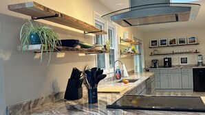 Une cuisine moderne dotée d’un îlot central, de tabourets de bar et d’étagères intégrées.