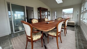 Une salle à manger avec une table en bois, six chaises, un buffet et une lucarne.