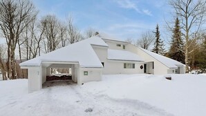 A modern house with a snow-covered roof, a garage, and a driveway. - Convenient townhouse w/ seasonal mountain views, pool, tennis, w/d, a/c, wifi (Warren)