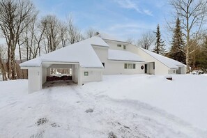 A modern house with a snow-covered roof, a garage, and a driveway. - Convenient townhouse w/ seasonal mountain views, pool, tennis, w/d, a/c, wifi (Warren)